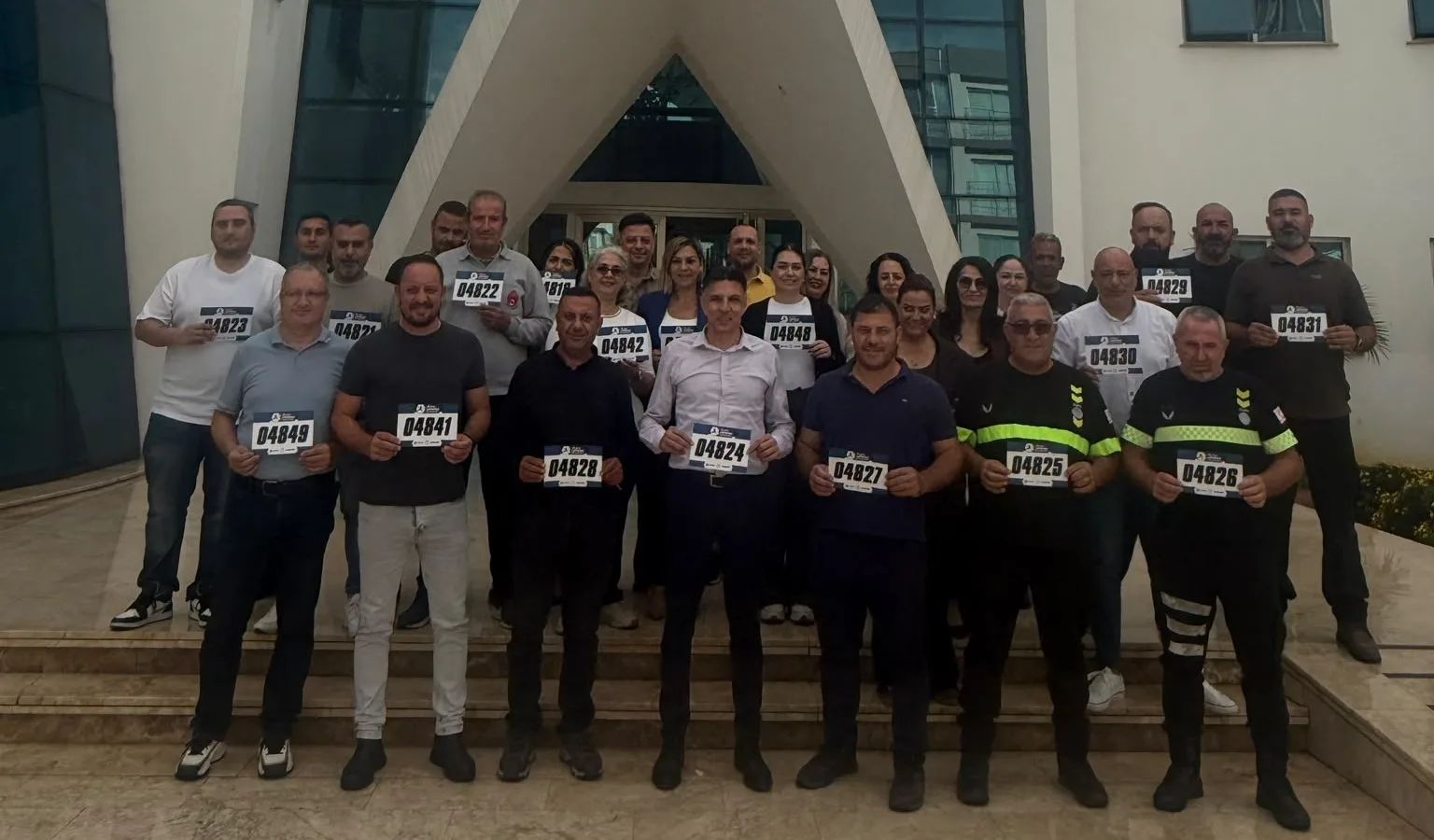Gönyeli-Alayköy Belediyesi çalışanları, Lefkoşa Yarı Maratonu göğüs numaralarıyla belediye binası önünde